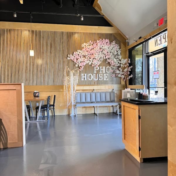 Interior of Pho House Suwanee with wooden slat walls, cherry blossom decor, and a gray bench.